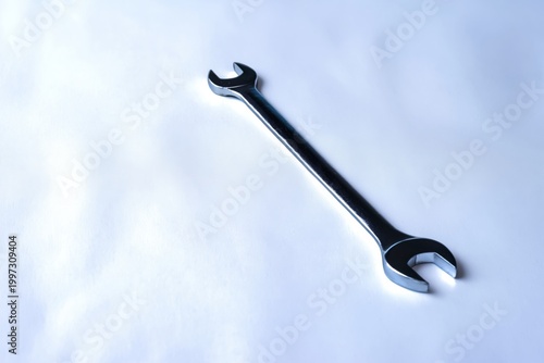 Metal Wrench Resting on a Plain White Surface in a Well-Lit Environment