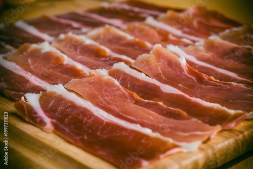 Cured Meat Slices Arranged Neatly on a Wooden Board for Preparation or Serving