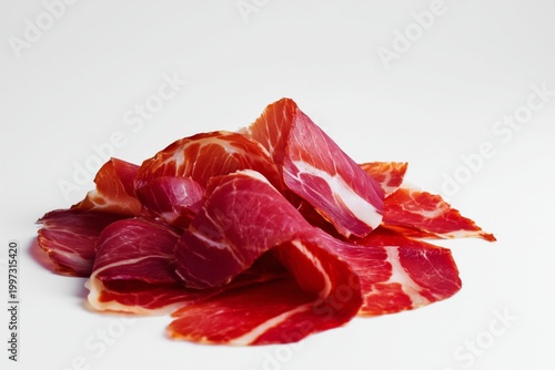 Slices of Cured Meat Arranged on a White Surface With Different Colors and Te...