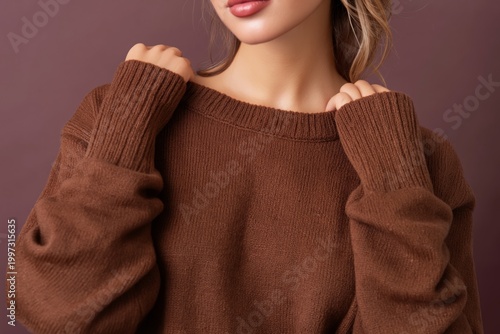 Model Poses With Hands in Sweater Against Solid Background During Indoor Fash...