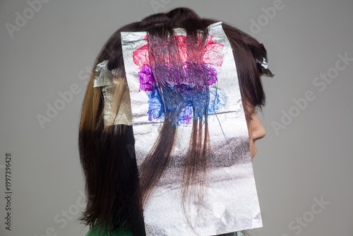 Foto Colorist painting rainbow colors on hair foil section using pink blue purple pig