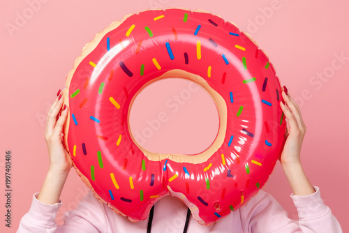 Cropped closeup view of faceless woman holding inflatable rubber ring for swimming and pool leisure holiday tropical vacation fun summer beach sunbathing resort trip isolated on pink background