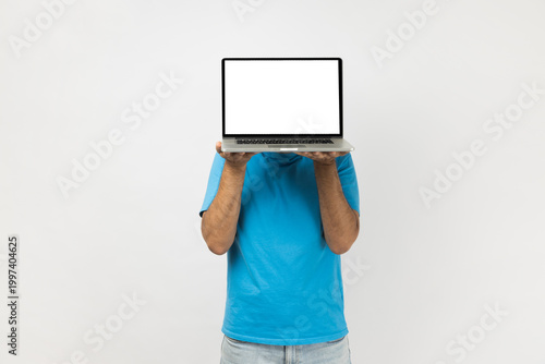 Portrait of unknown anonymous man wearing blue T- shirt standing holding notebook with empty white display, advertisement area, promotion. Indoor studio shot isolated on gray background.