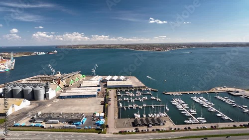 Aerial panorama of  marina with boats, coastal industrial port with storage tanks, silos, warehouses and shipping infrastructure  Industrial port, marina and coastal cityscape Fredericia.