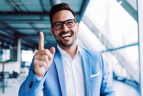 Man Smiles and Points While Standing in Modern Office Space During Daytime
