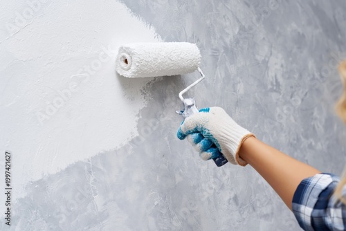 Person Painting a Wall With a Roller in a Light Grey Color During a Home Impr...