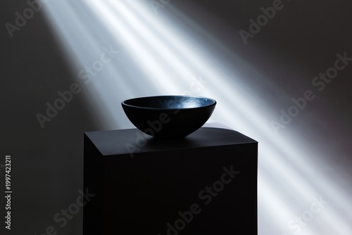 Black Bowl on a Pedestal With Light Rays Shining From the Top in a Dark Room ...
