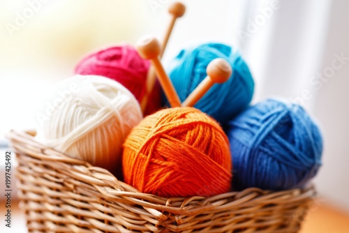 Yarn in a Basket With Knitting Needles and Flowers in the Background on a Bri...