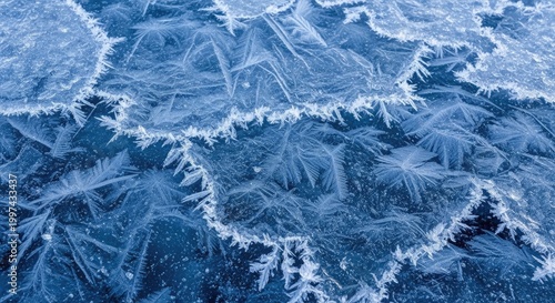 Ice patterns on a frozen lake, with a blue tint, creating a textured and intricate design.