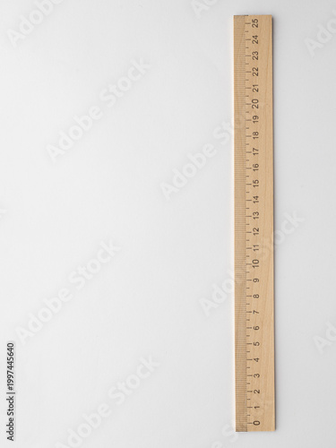 On a white background there is a wooden ruler for taking pictures of the product blank