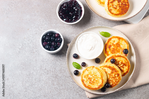 Photos Traditional cottage cheese pancakes served with sour cream, blueberry jam and fresh berries
