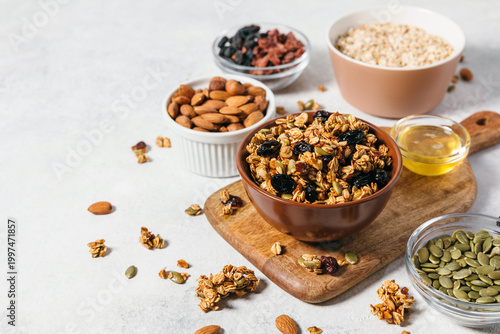 Fotografía Crunchy organic homemade granola clusters served in a brown bowl surrounded by raw ingredients like oats, nuts, and honey