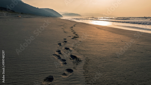 Foto Footprints on a Sandy quiet Beach at Sunset