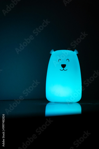 Bear shaped glowing night light lamp in dark background.