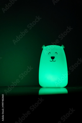 Bear shaped glowing night light lamp in dark background.