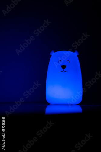 Bear shaped glowing night light lamp in dark background.