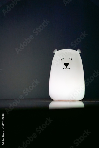 Bear shaped glowing night light lamp in dark background.