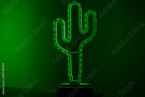 Green neon cactus lamp glowing in dark background.