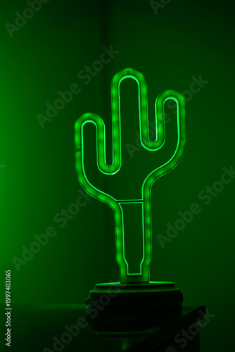 Green neon cactus lamp glowing in dark background.