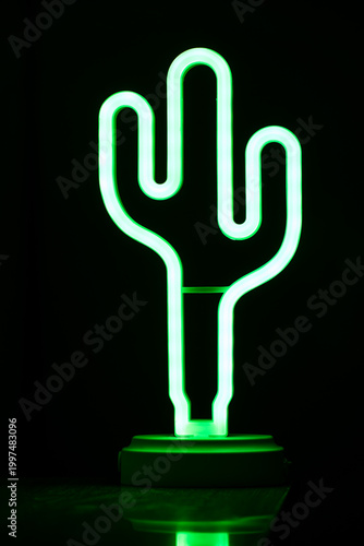 Green neon cactus lamp glowing in dark background.