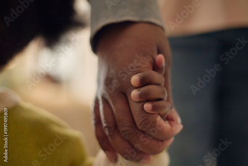Obraz na plátne Close up of Black parent holding child hand, walking together and expressing poverty, care, protection, and family support