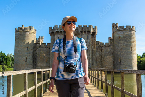 Young Female Tourist with Camera at Bodiam Castle in Bodiam, East Sussex, England, UK