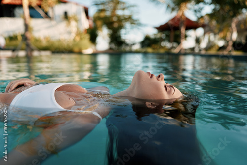 Cuadro en lienzo Relaxed person floating on their back in a tranquil pool, sunlit water and a reflective surface, capturing a lifestyle moment of leisure, wellness, and self care, and calm mood