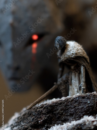 Miniature cloaked figure with sword on mossy branch
