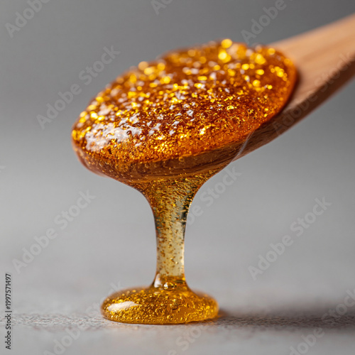 Golden honey dripping from spoon closeup