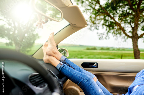 Woman relaxing barefoot with feet on car dashboard