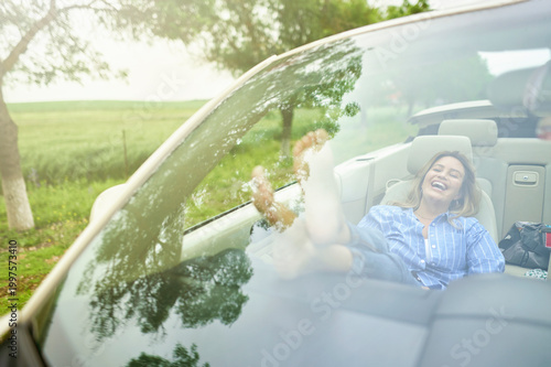 Woman relaxing in convertible car feeling freedom and adventure
