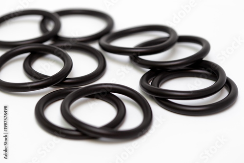 Top view macro shot of multiple black rubber O-ring seals arranged in a geometric pattern on a clean white background, showcasing industrial sealing components