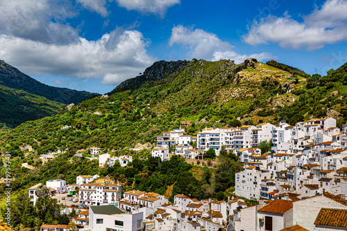 Pueblo blanco andaluz de Casares escalonado en la montaña verde bajo cielo azul con nubes concepto de vida lenta destino idílico y arquitectura tradicional mediterránea en España