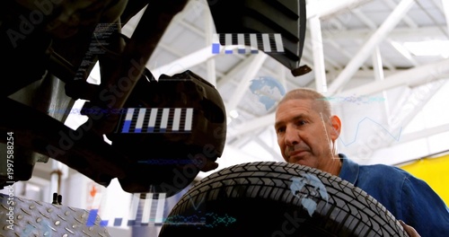 Inspecting mechanic in blue work shirt holding tire-wheel assembly in garage with digital overlay