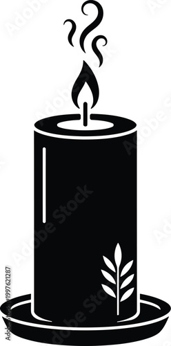 Black candle with leaf design burning on plate for decoration or ambiance