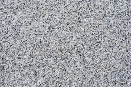 A close up shot captures the detailed grainy and speckled texture of a natural grey granite stone surface