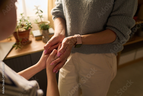 Close up of Caucasian adult woman holding child hands, offering comfort and reassurance at home. Suitable for parenting support, caregiving, trust, empathy, family counseling themes