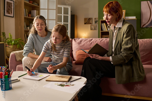 Canvas Print Young girl drawing during counseling session with mother and female therapist, addressing child mental health and family support