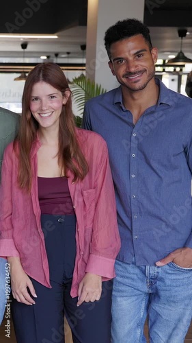 Vertical HD video of multiracial business couple smiling together at office workplace. Two professionals collaborating and enjoying teamwork in a modern corporate environment