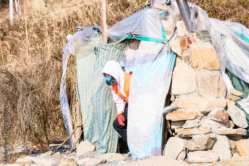 Canvastavla Worker bending to inspect entrance of makeshift hut