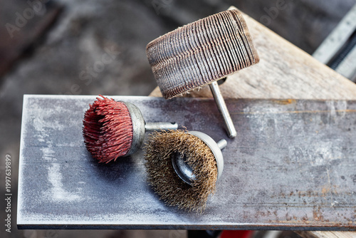 Fényképezés Industrial attachments for power drills including wire cup brush, nylon abrasive brush and flap wheel on a steel plate