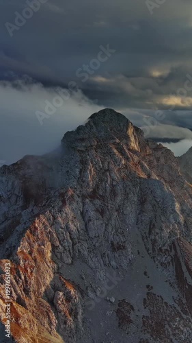 Aerial around view of amazing rocky mountains in clouds at sunset. Vertical video 4k