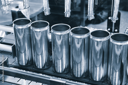 factory conveyor moves aluminum cans for beer  carbonated beverages through automated equipment. Metal levers precisely place lids on  cans. industrial setting exemplifies precision and efficiency.