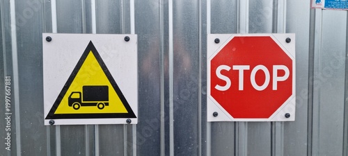 Industrial stop sign and truck warning sign on metal wall.