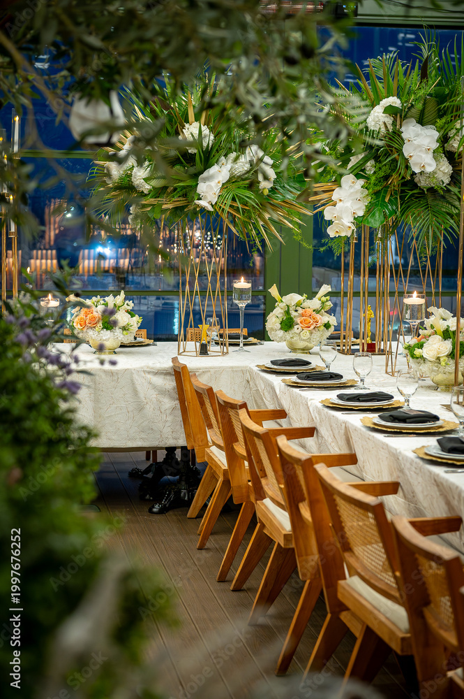 Obraz premium Elegant dinner setup in a garden space. Tables are arranged in a garden area with flowers and decorative items.