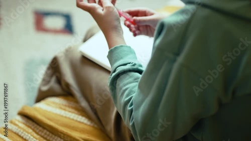 Smart Little Girl in Big Glasses Writing in Notebook while Sitting on Couch with Stack of Books — Cinematic 4K 10-bit