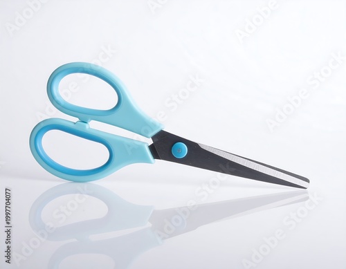 Overhead shot of a pair of scissors with turquoise handles and a dark metal blade, casting a reflection