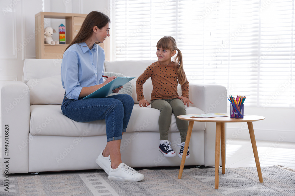 Obraz premium Professional psychologist working with little girl on sofa indoors