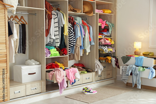Many different messy clothes in wardrobe indoors