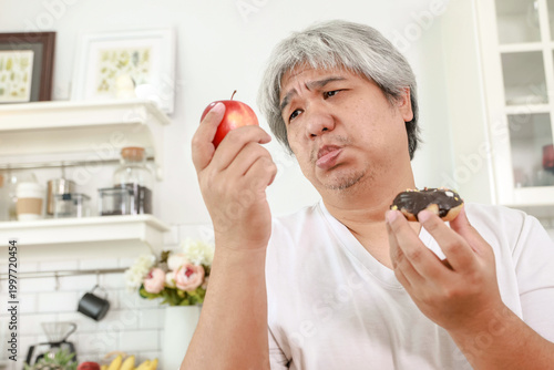 Obraz na plátně The obese man appears to prefer the sugary donut over the apple, seemingly unconcerned about the risk of diabetes : Nutritional concepts for obese people